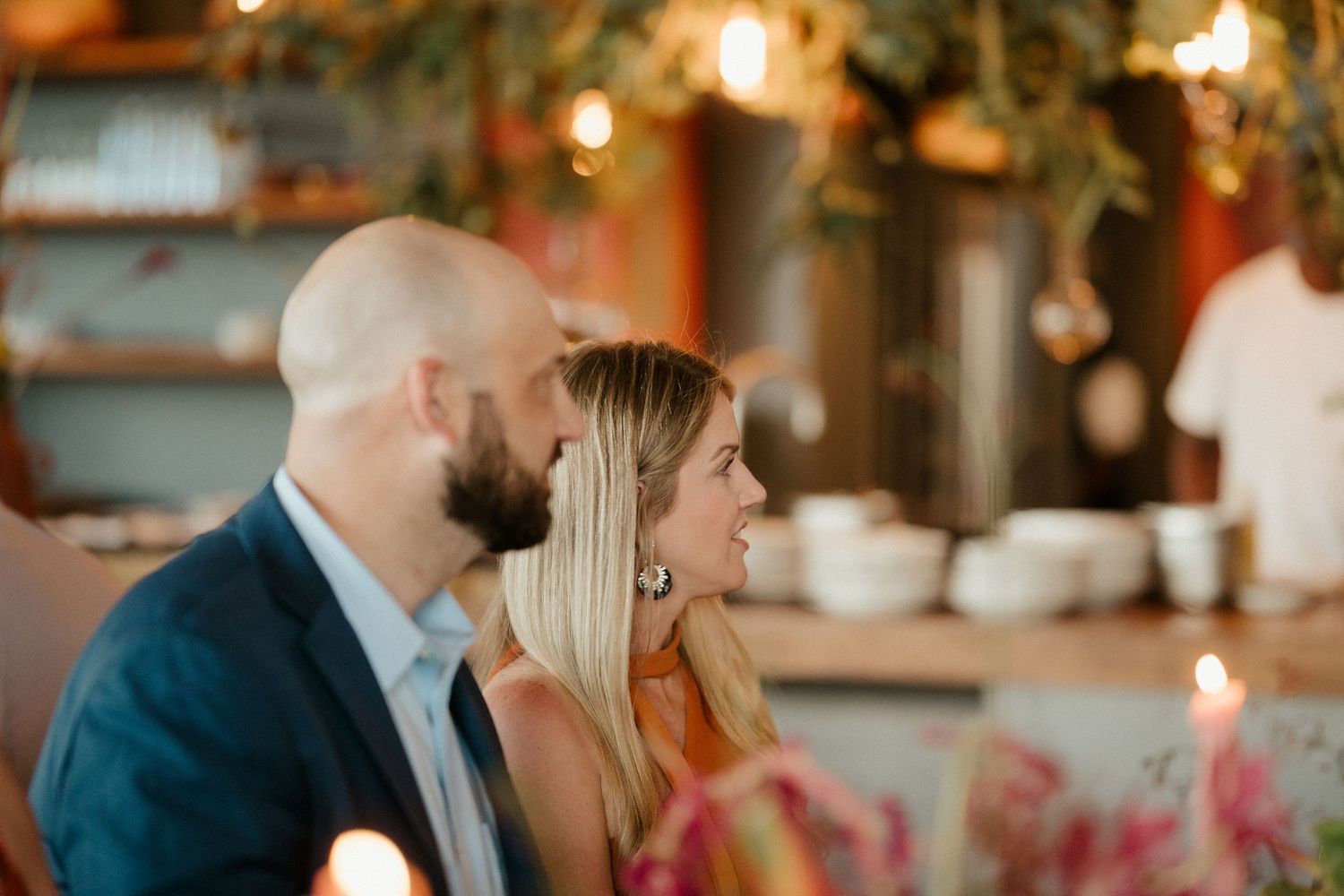A romantic candlelit dinner scene with soft lighting and pink floral decorations.