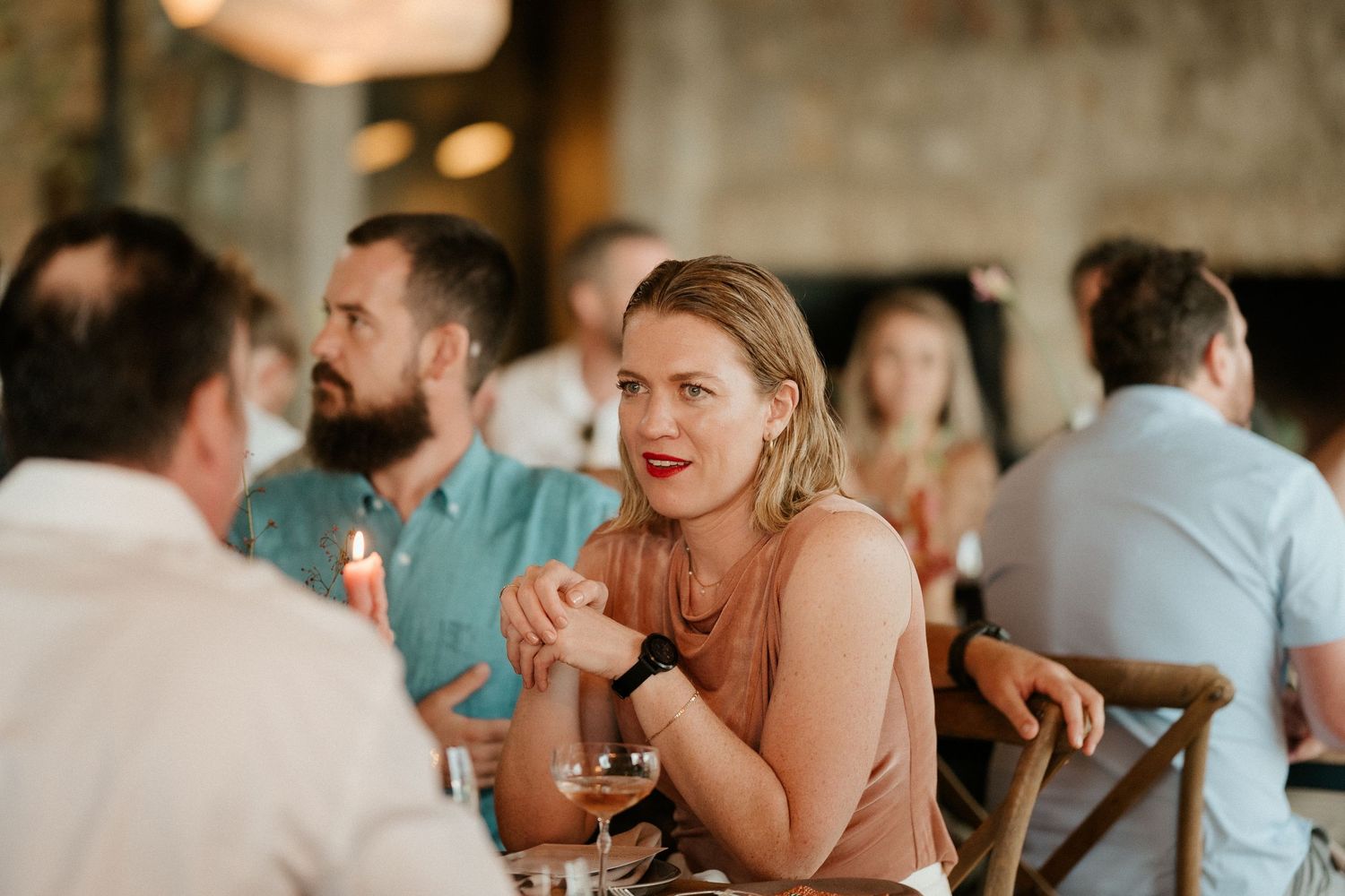 Candid reception moment with guests engaged in lively conversation at rustic venue.