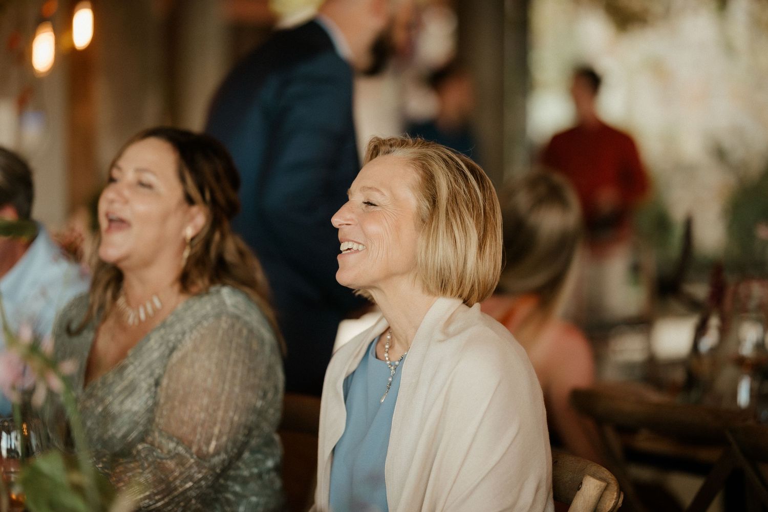 Wedding guests sharing genuine laughter during reception celebration.