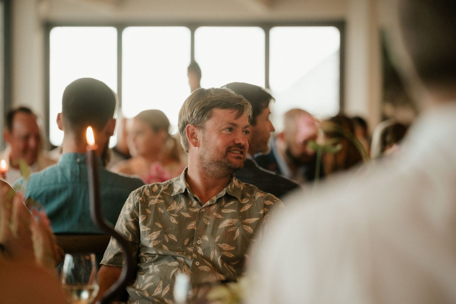 A casual reception dining scene with guests gathered around tables indoors.