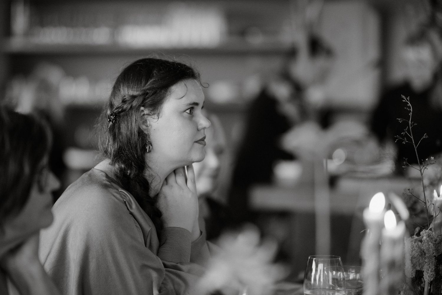 A black and white photo of guests having a thoughtful conversation at an intimate dinner gathering.
