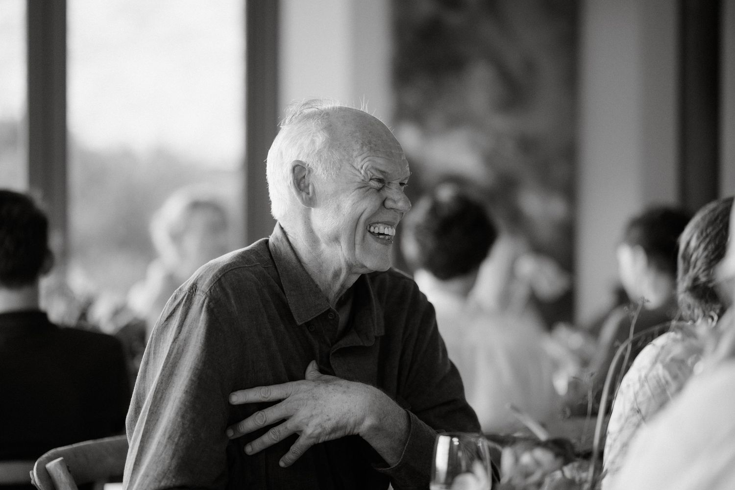 A candid black and white photo of an elderly guest enjoying a lively moment at an event.