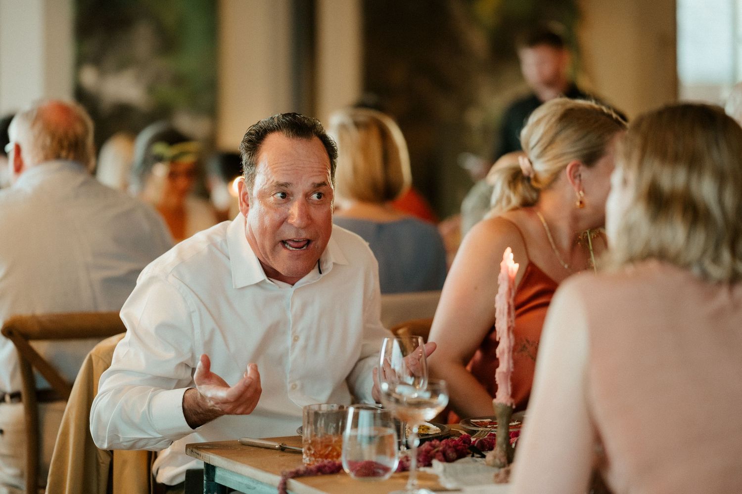 Guests engaged in animated dinner conversation at a casual restaurant setting.