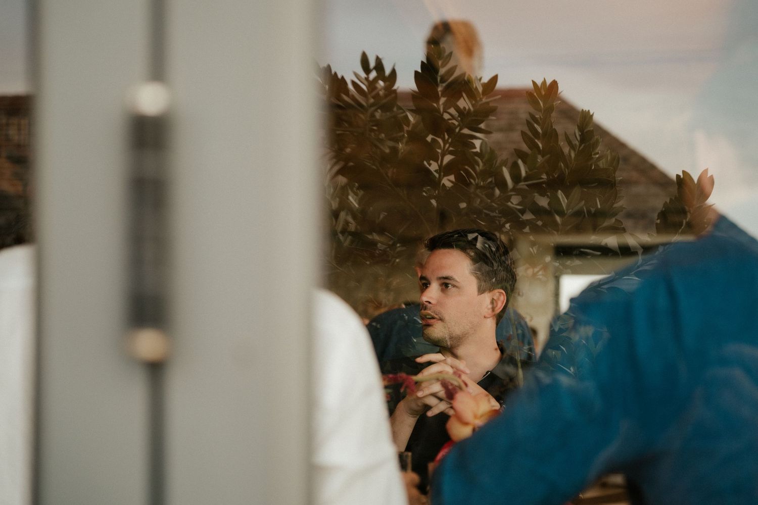 Intimate indoor wedding moment captured through decorative foliage.