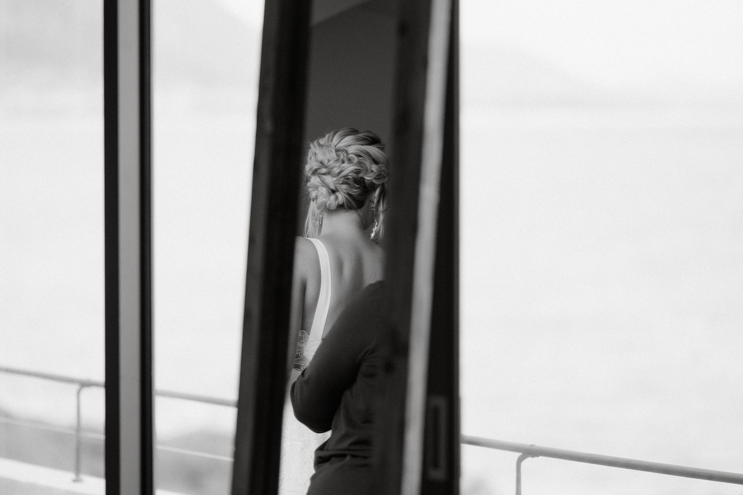 An artistic black and white photograph showing a silhouetted figure through a window.