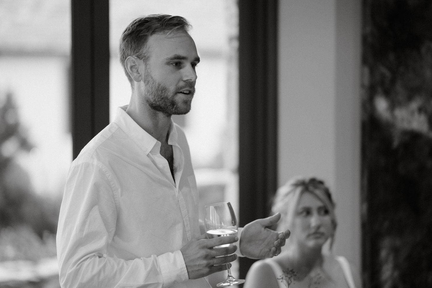 Elegant wedding reception scene with person giving toast while holding wine glass.