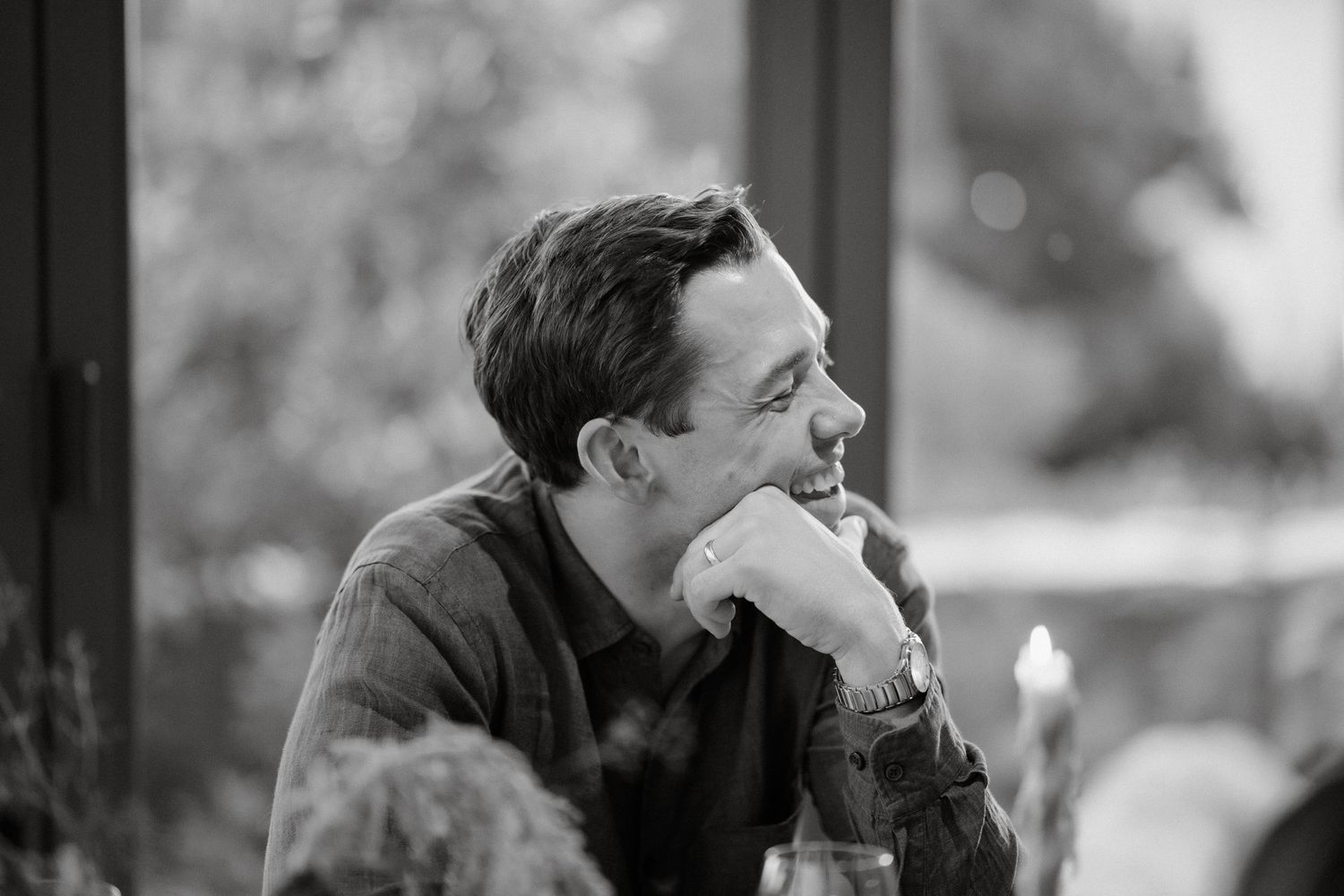 Black and white portrait of person in contemplative pose resting chin on hand.