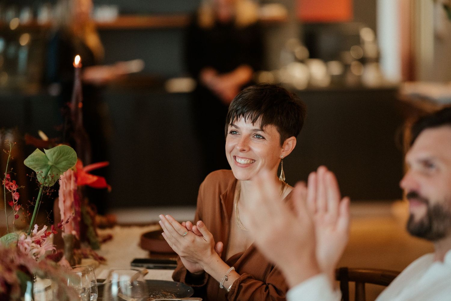 Candid moment of dinner guests laughing and celebrating at restaurant table.