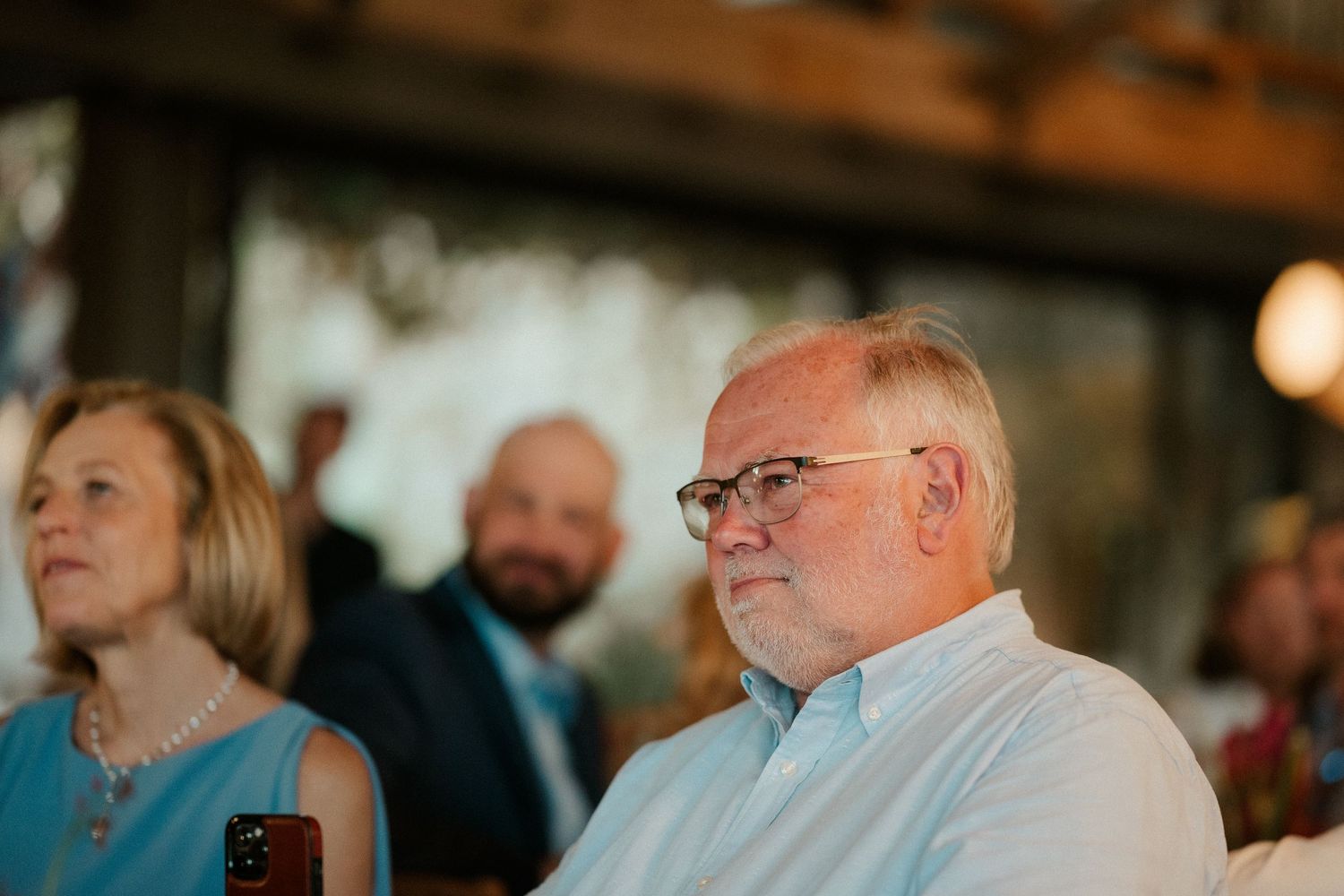 Guests attentively watching a wedding reception event indoors.
