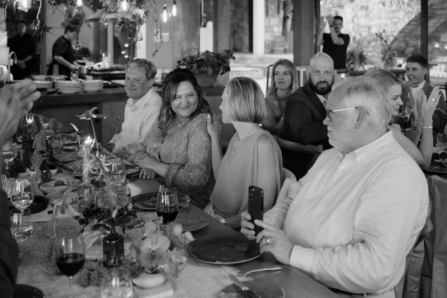 A black and white photo of wedding guests seated at a formal reception dinner.