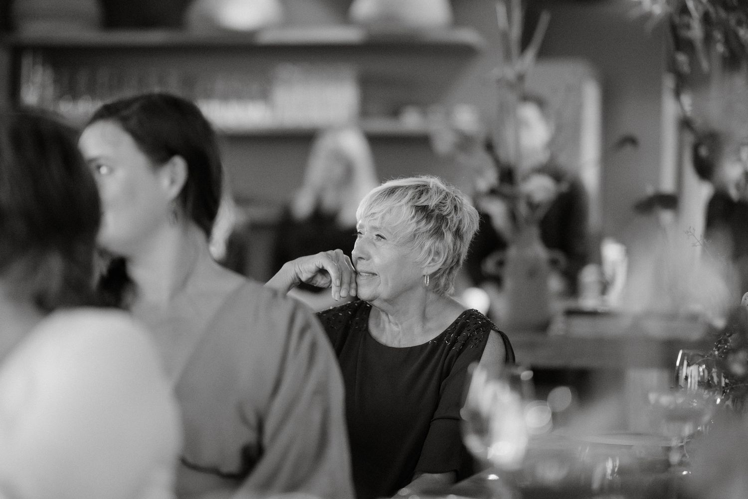 Black and white candid photo of guests enjoying conversation at dinner gathering.