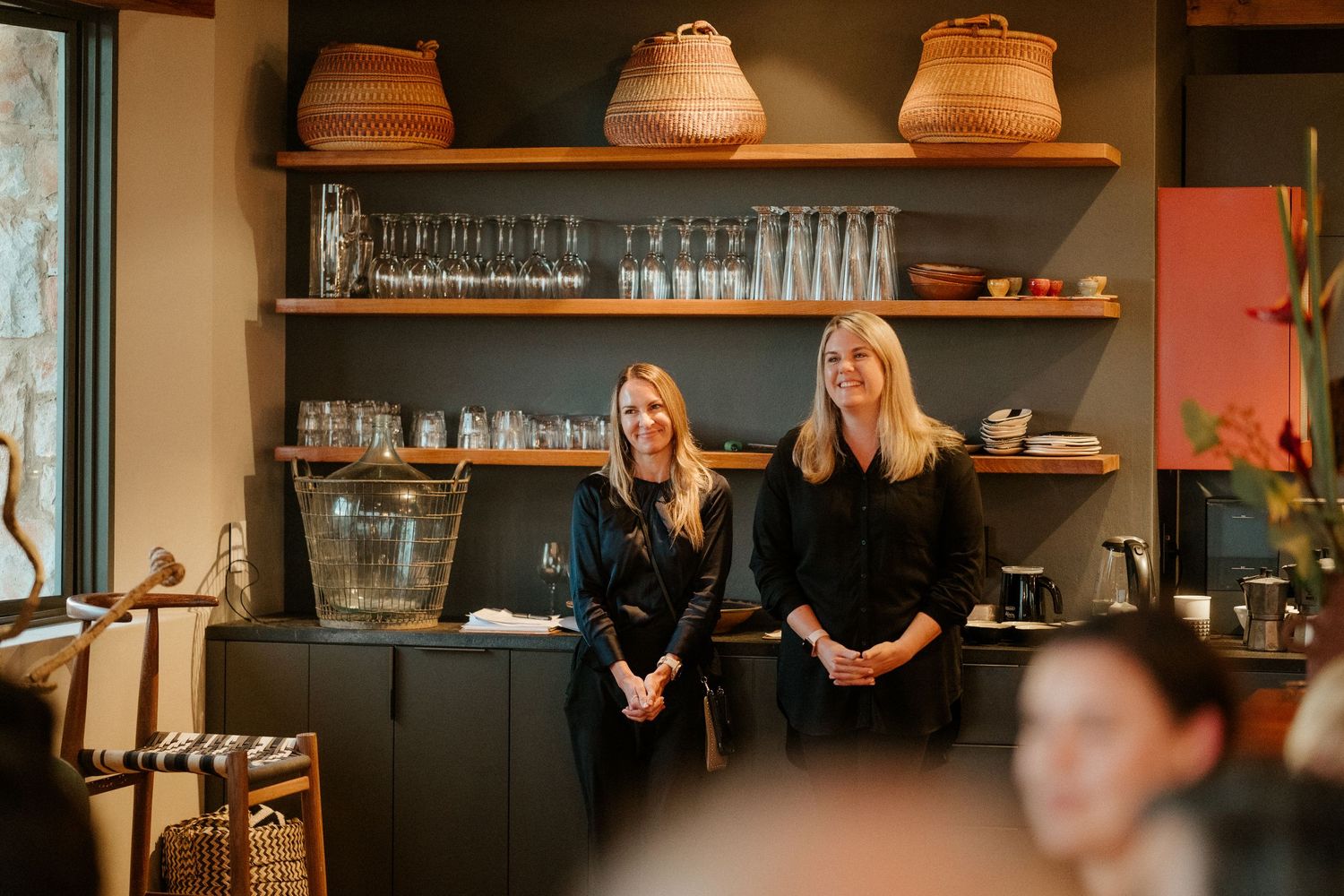 Modern cafe interior with wooden shelving displaying glassware and baskets.