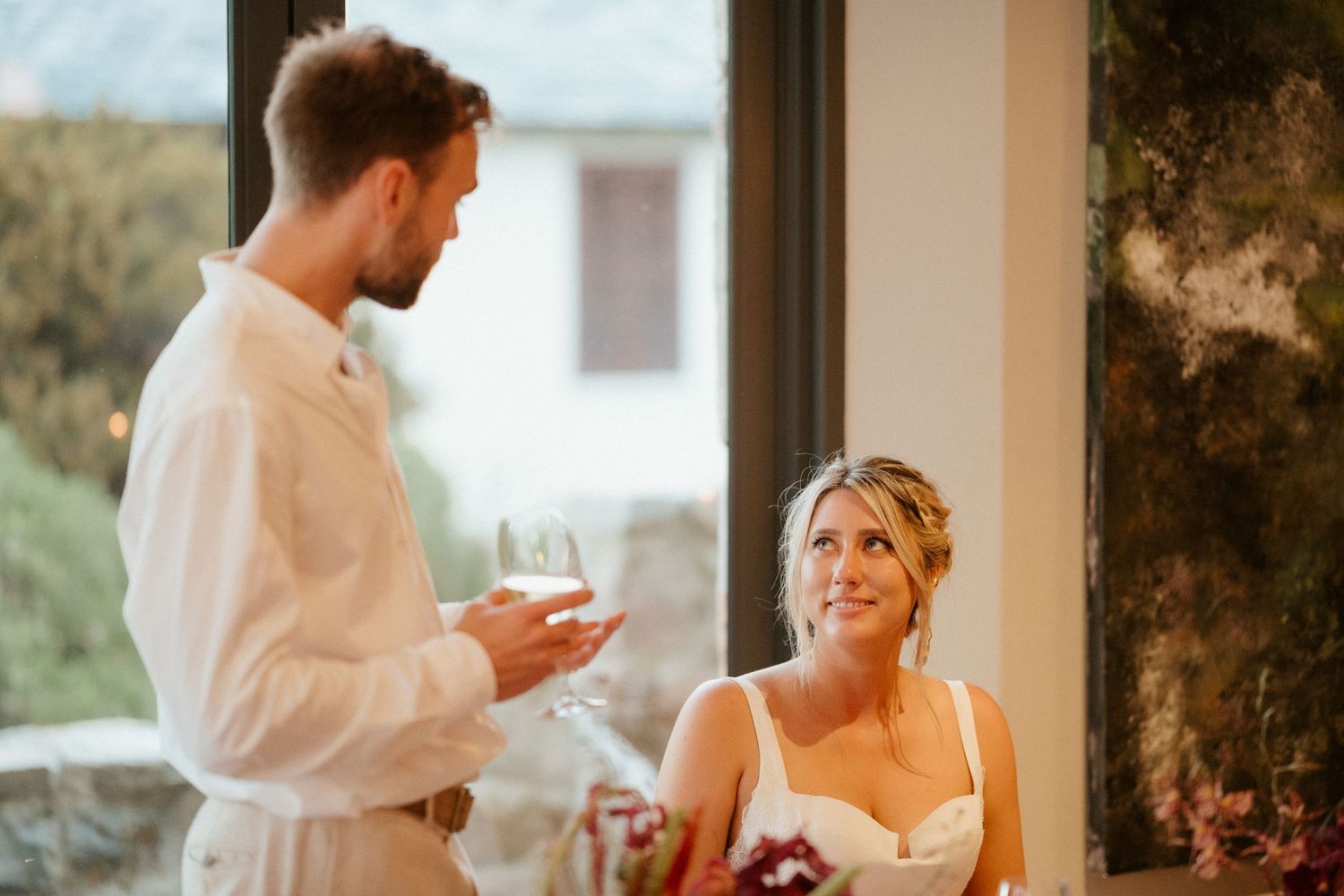 An intimate moment captured during a wedding toast in natural window light.