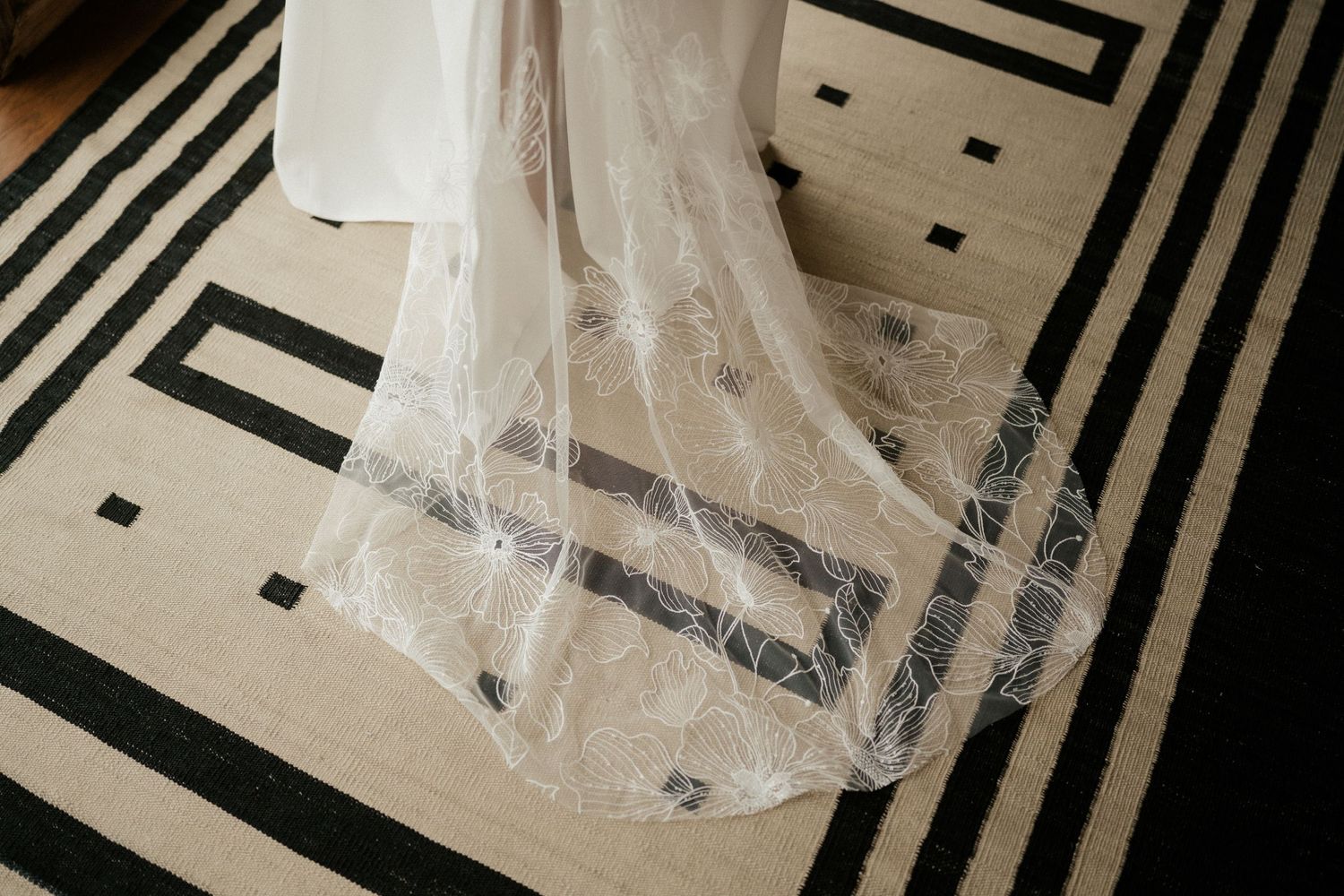 Delicate white lace wedding veil detail against a geometric black and white patterned floor.