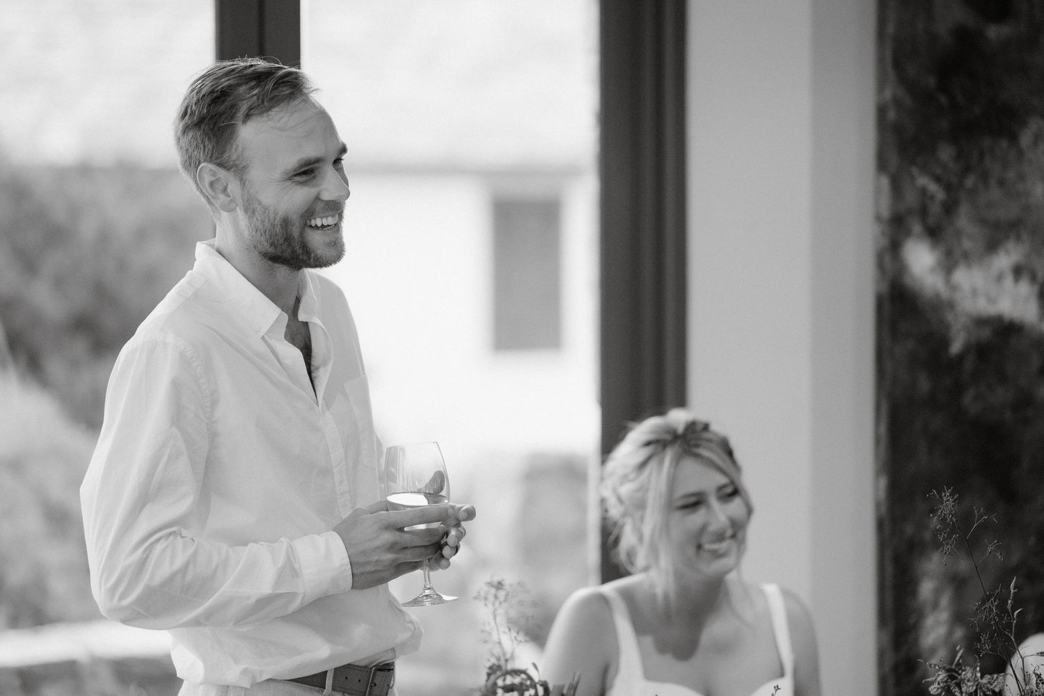 Black and white candid photo of guests enjoying drinks during celebration.