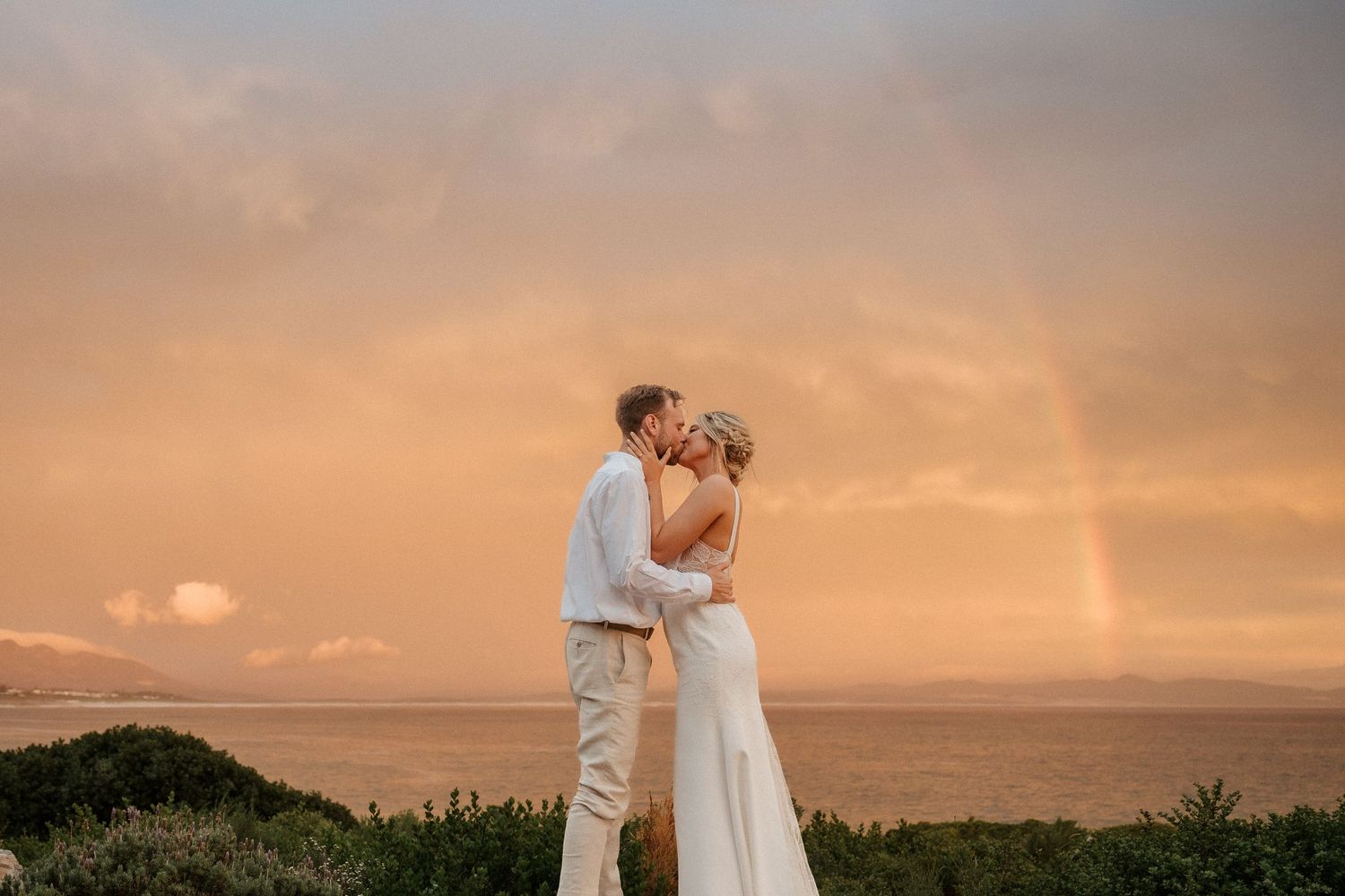A romantic sunset embrace with ocean views and golden sky in the background.