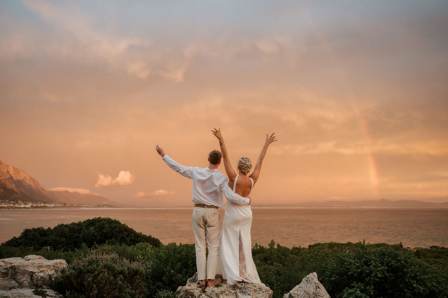 Celebratory pose against a golden sunset sky overlooking the ocean.