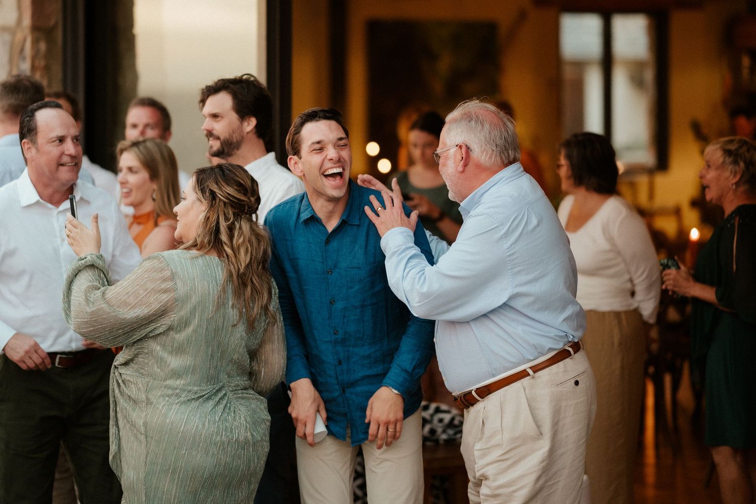 Wedding guests sharing laughter and conversations during an indoor reception celebration.