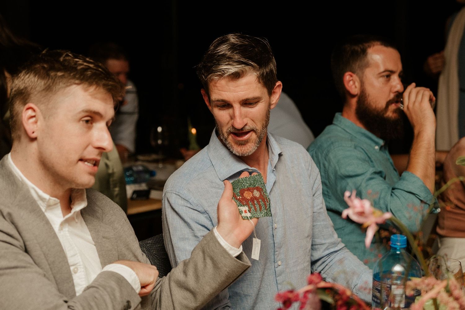 Wedding guests enjoying drinks and conversation at a dimly lit reception table.