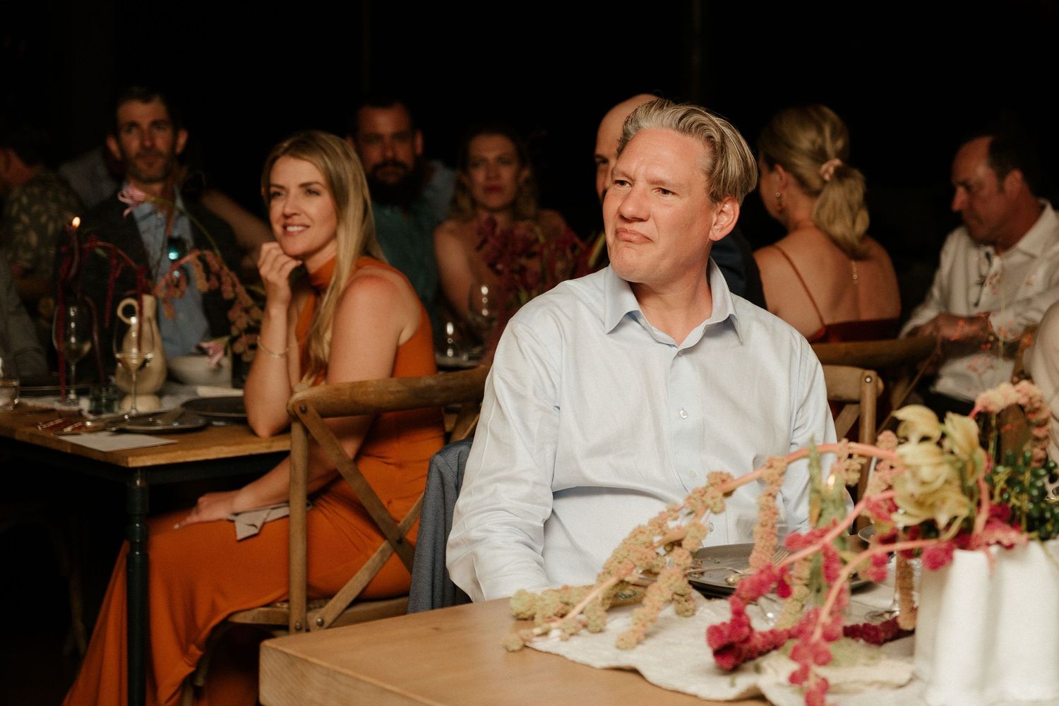 Candid shot of dinner guests seated at a decorated table during evening celebration.
