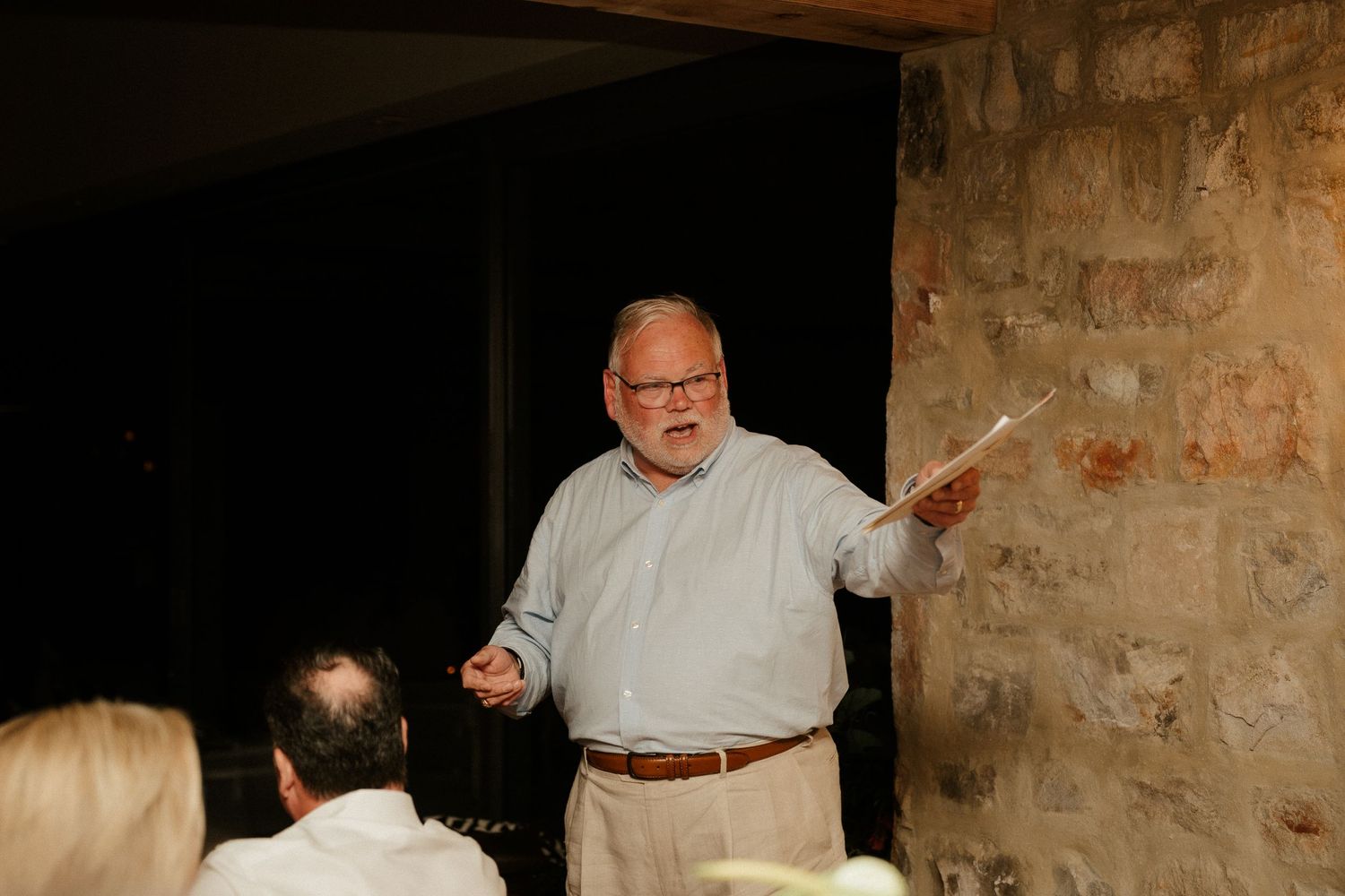 A speaker gestures while delivering remarks at a wedding reception.
