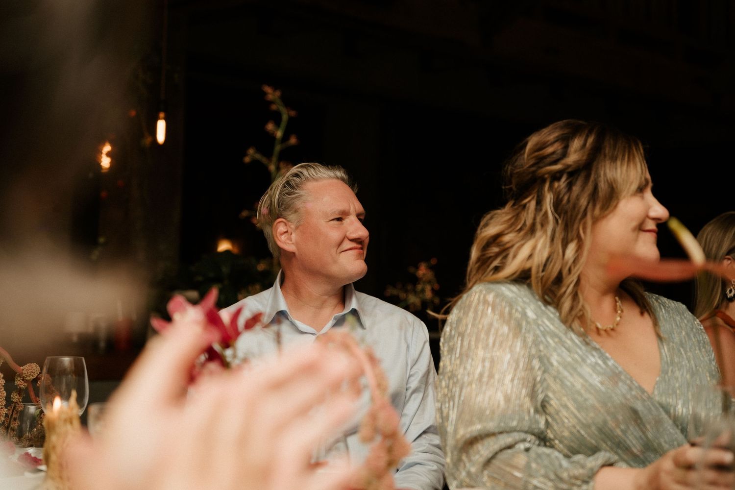 Candid reception moment captured in warm lighting with natural expressions.