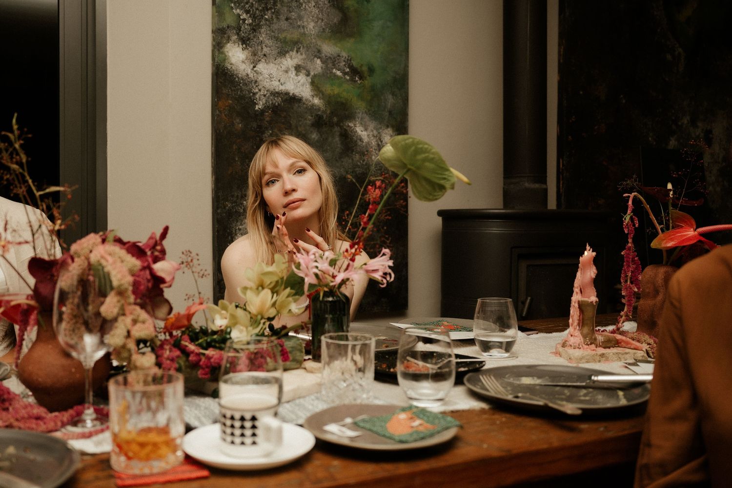 Decorated dinner table with autumn floral arrangements and place settings in warm candlelight.