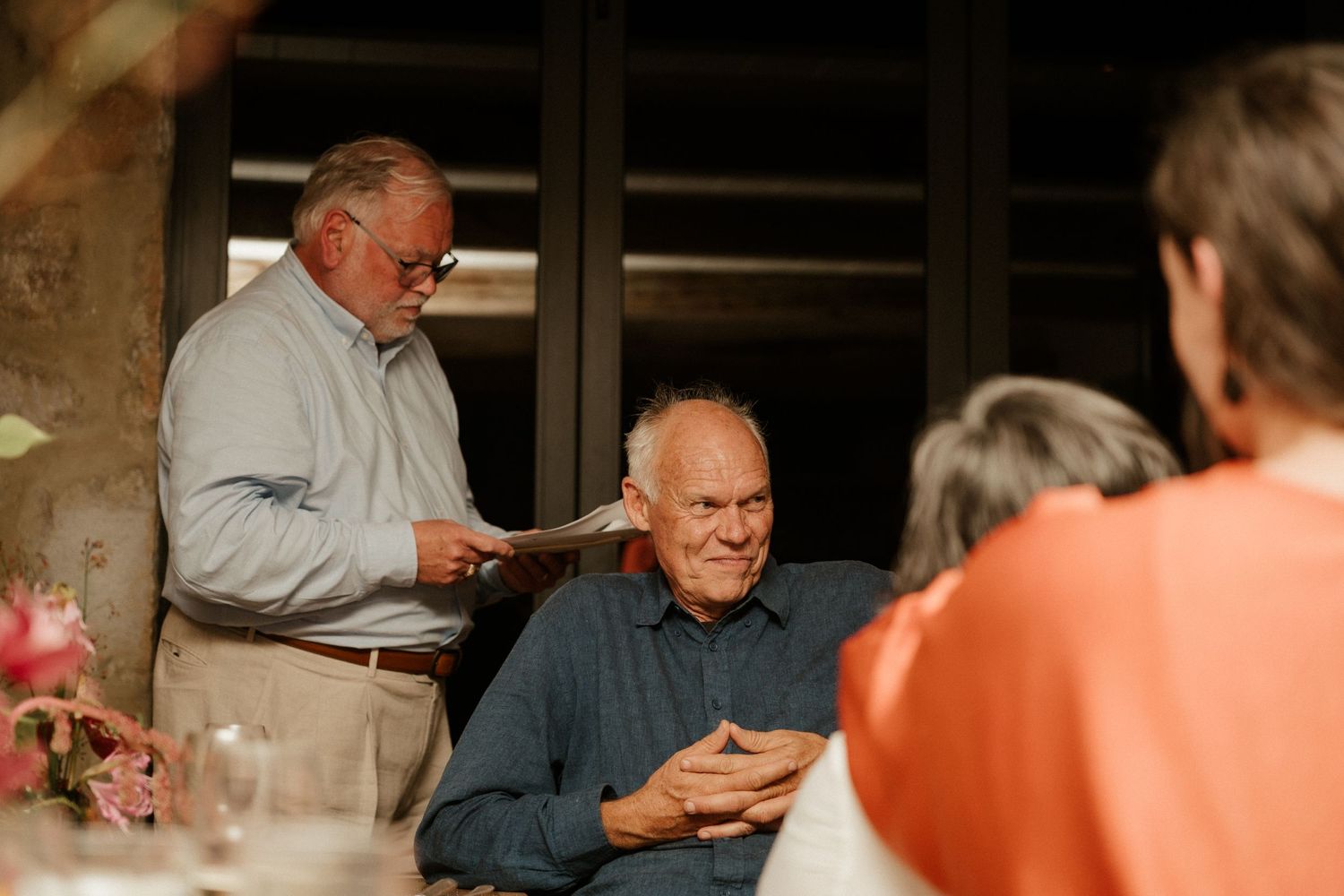 A casual gathering of elderly guests enjoying conversation at a dinner table.