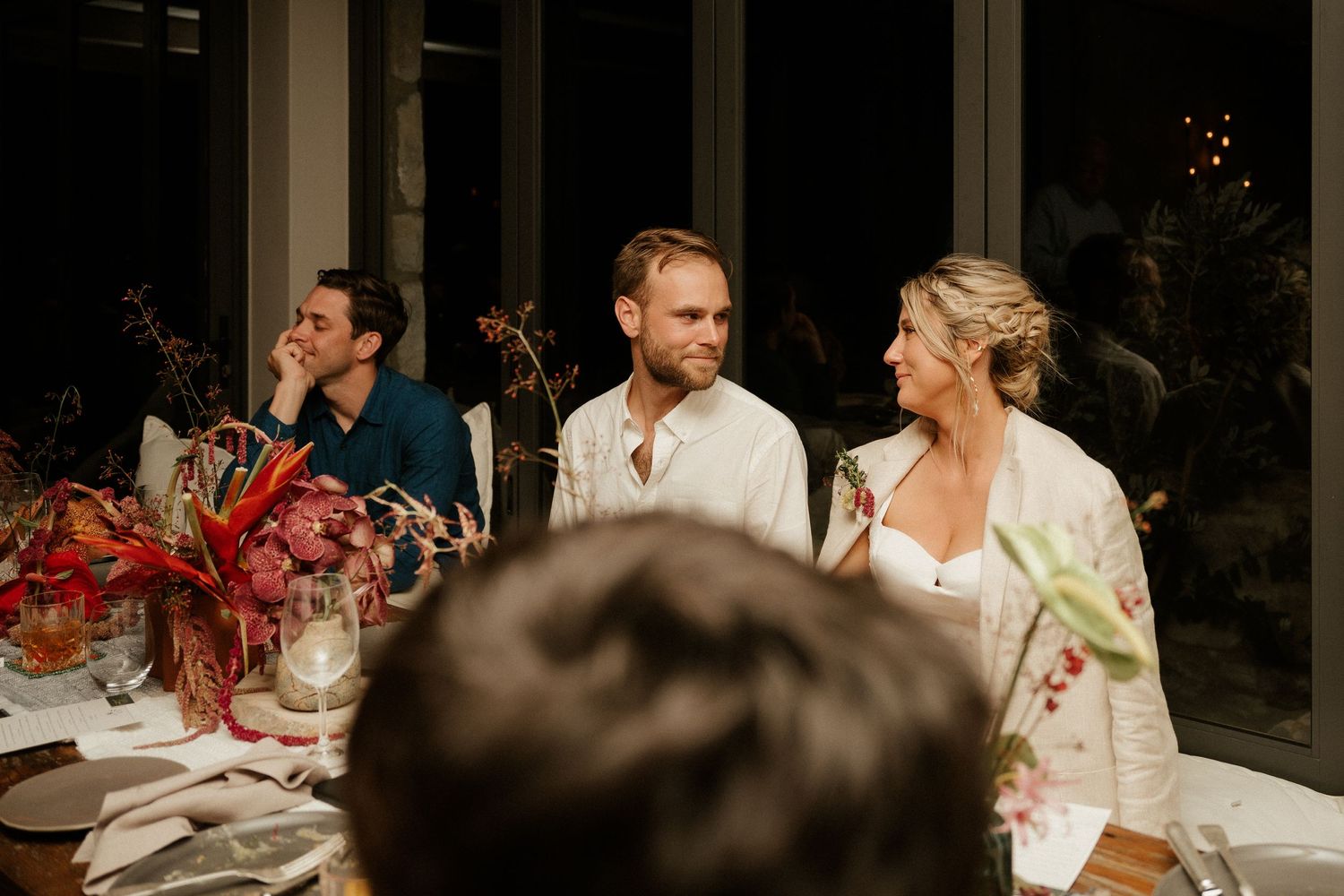 Guests enjoy an elegant wedding reception with floral centerpieces and mood lighting.
