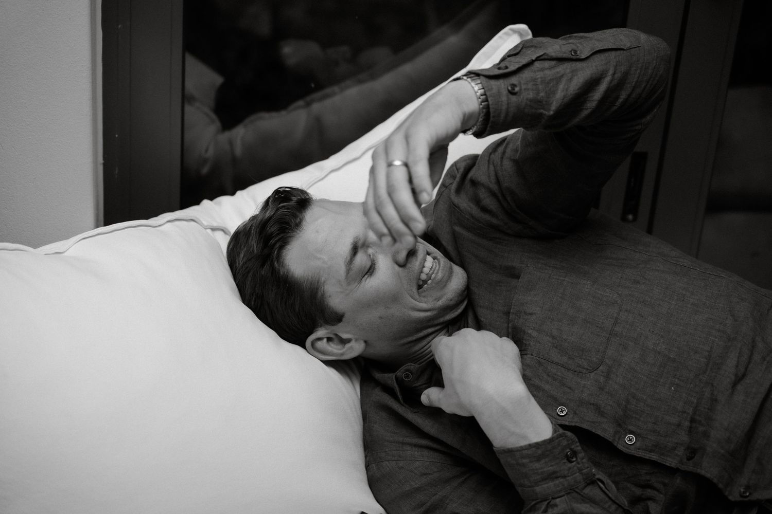 A black and white photo captures someone laughing heartily while lying down.