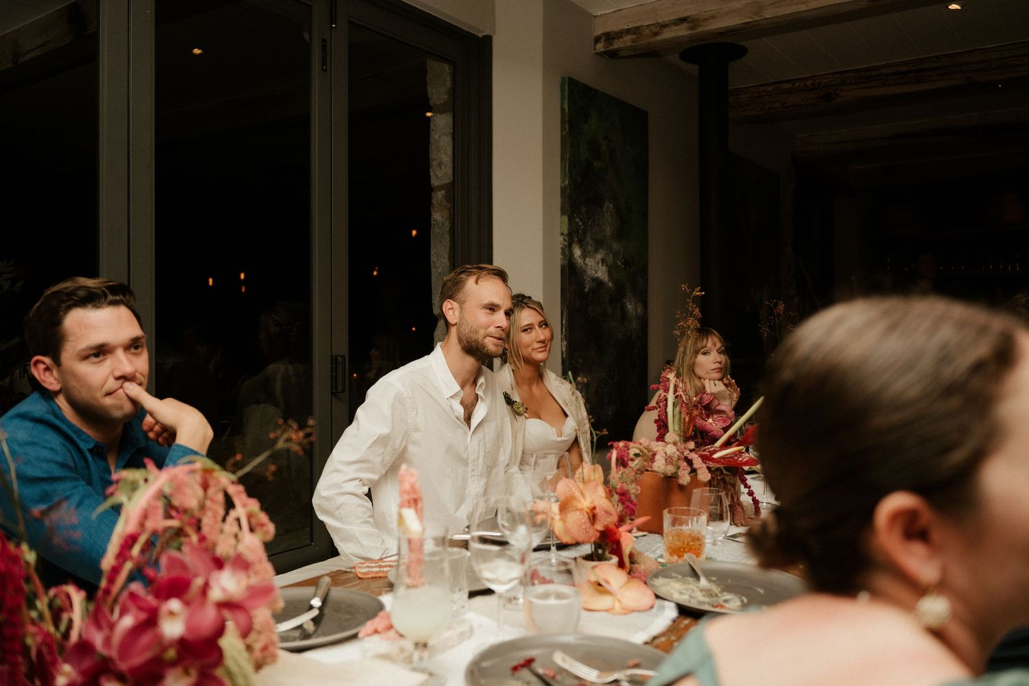 Dinner guests gathered around a table with wine glasses and floral decorations.
