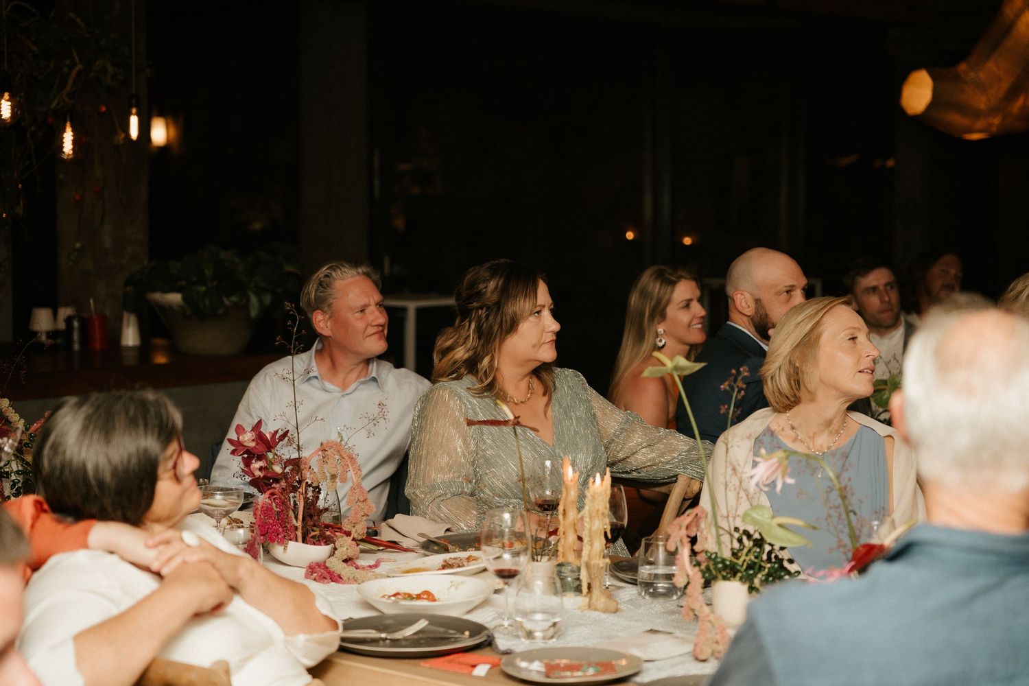 Dinner guests enjoying conversation and laughter at an elegantly set wedding reception table.