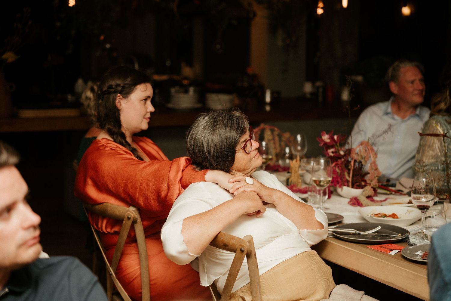 Diners enjoy an intimate meal at a rustic restaurant table with ambient lighting.