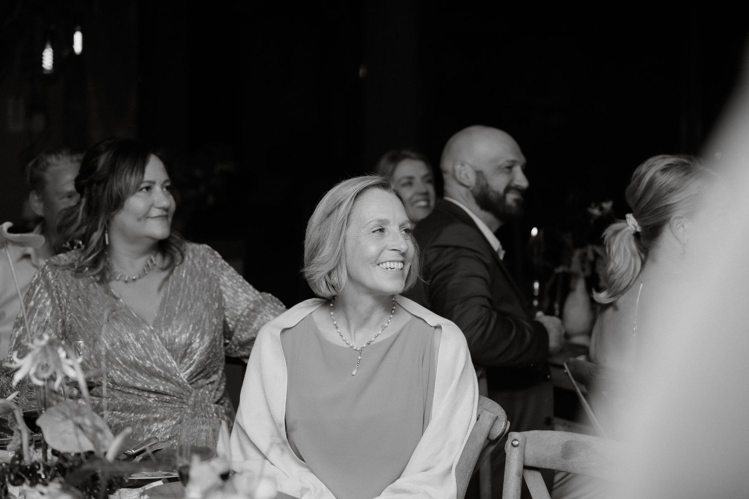 Wedding guests enjoying candlelit reception dinner in black and white photography.