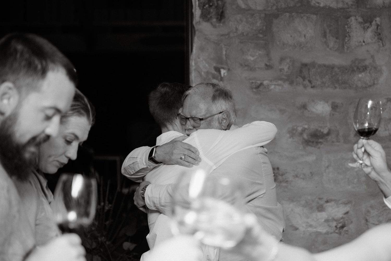 Emotional black and white photograph of guests embracing at celebratory event.