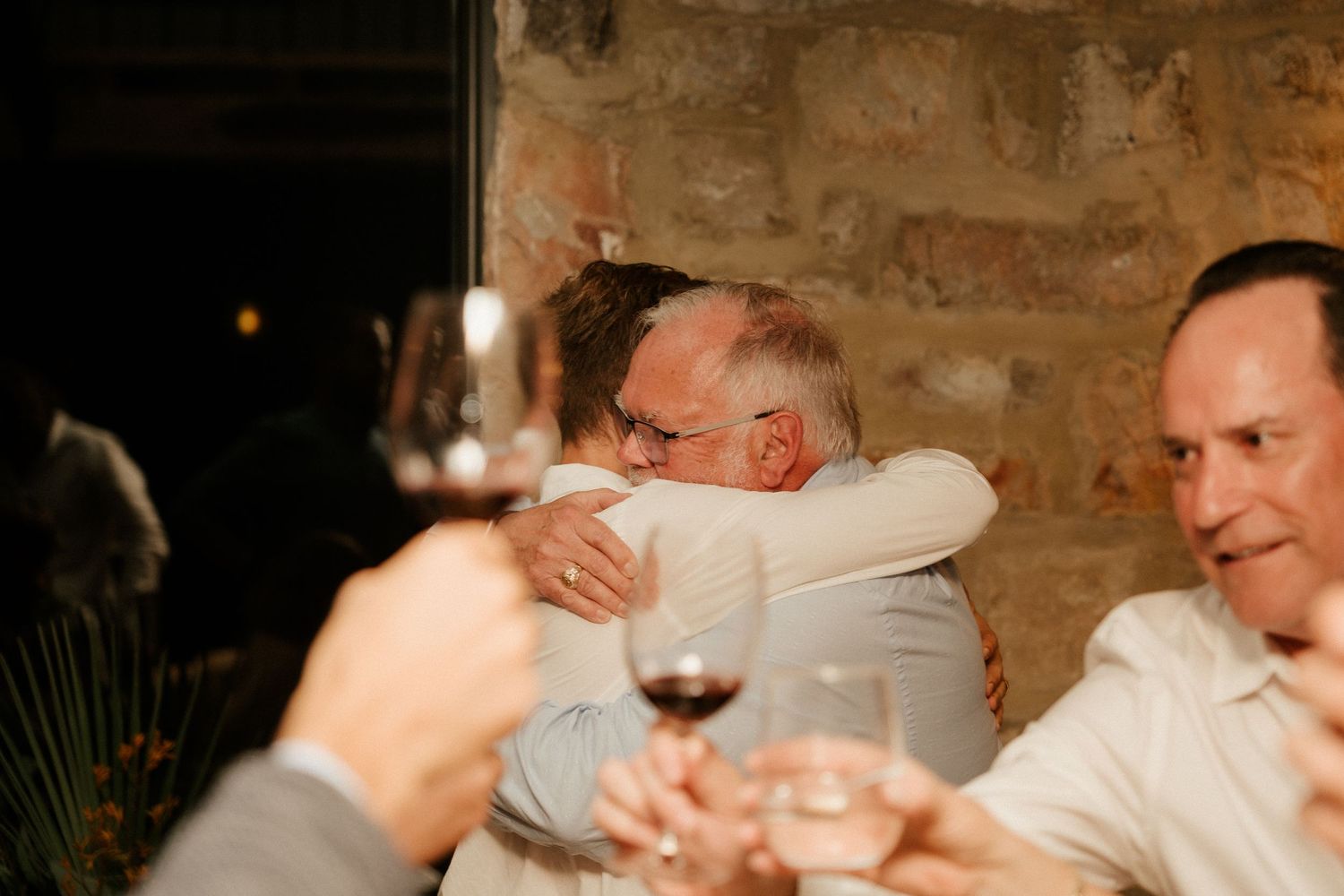 Warm embrace shared between guests during wine dinner celebration.