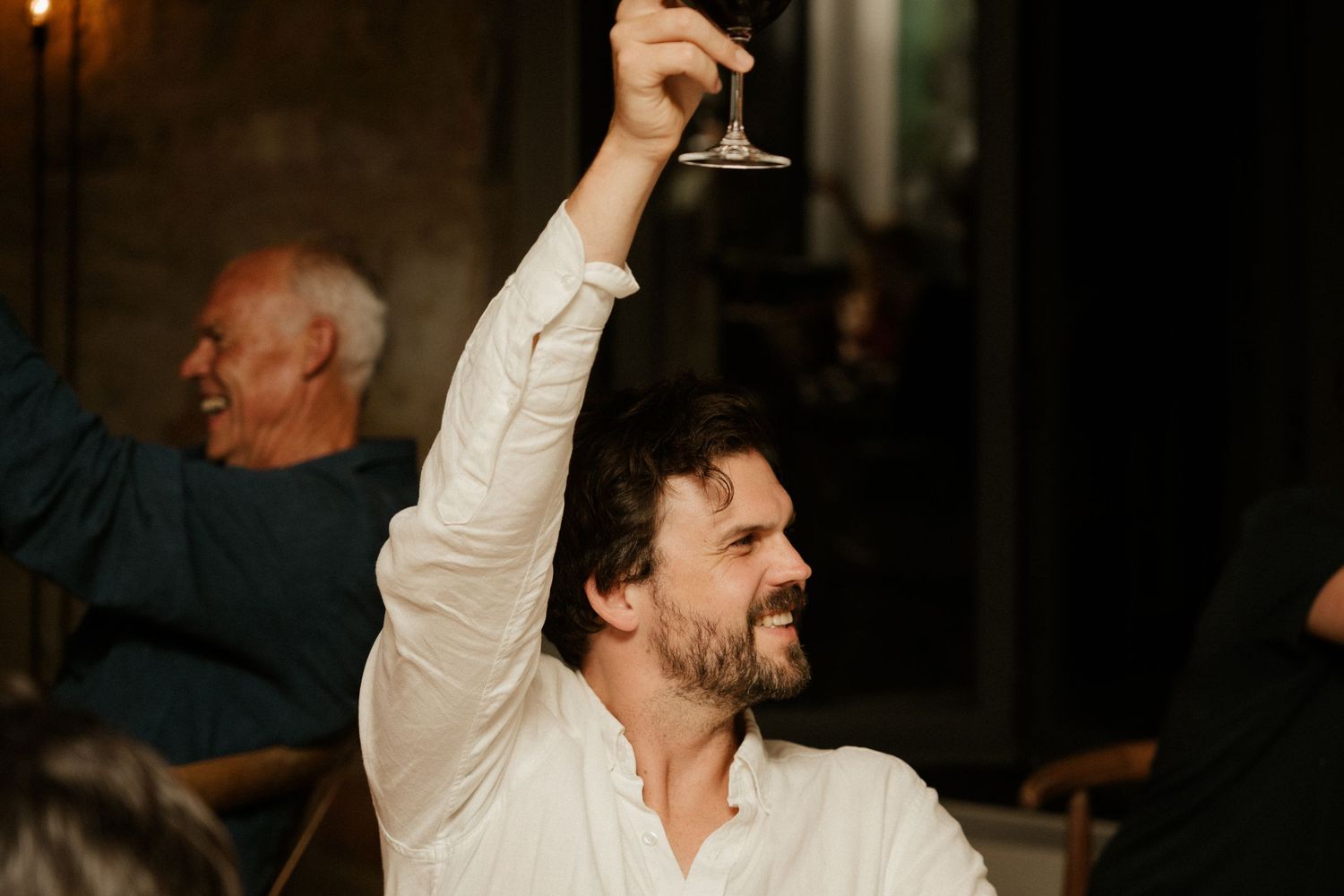 Guest raises a wine glass in celebration during a dinner party.