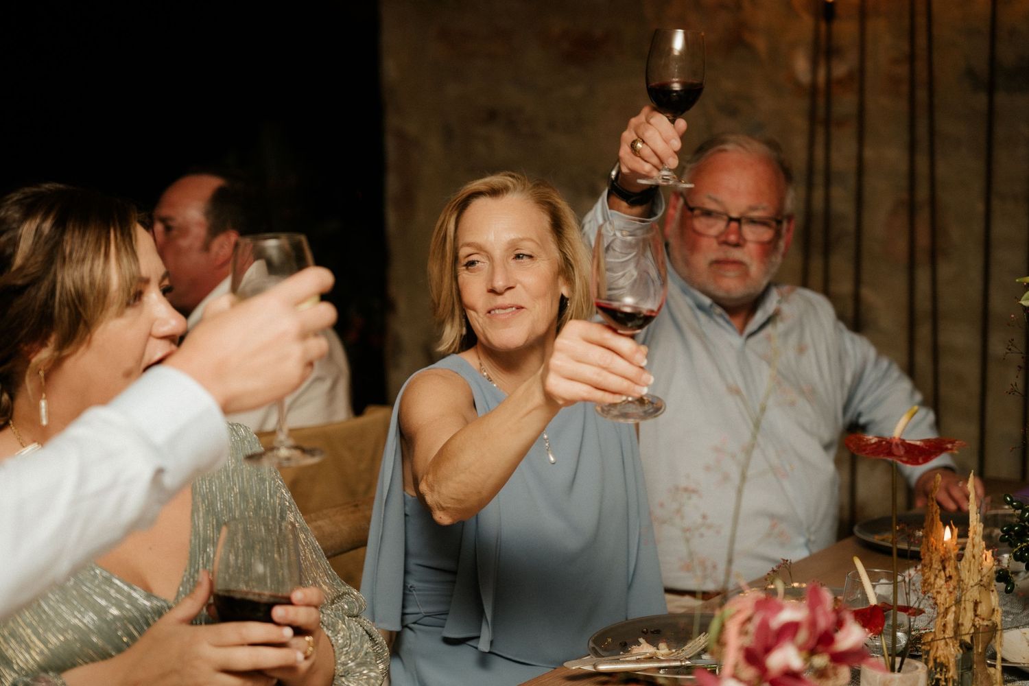 Wedding guests raise their wine glasses in celebration during a reception dinner.