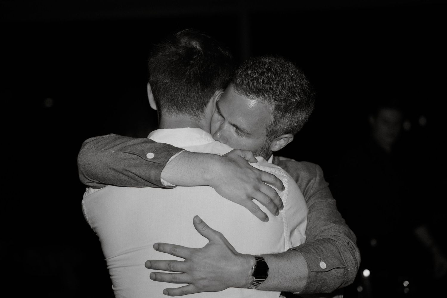 Black and white candid photograph capturing emotional embrace during celebration.