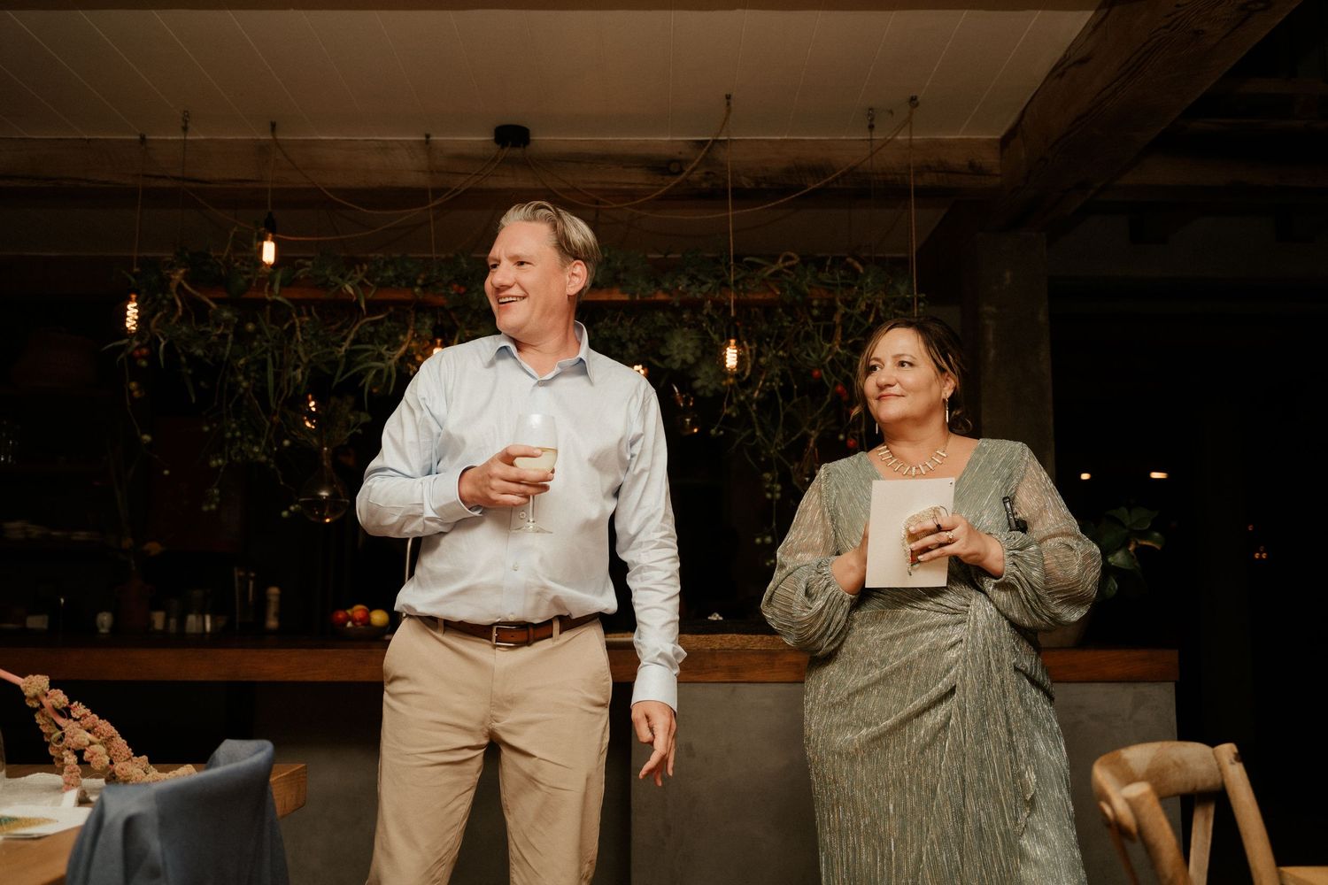 Guests enjoying drinks and conversations during an indoor evening celebration event.