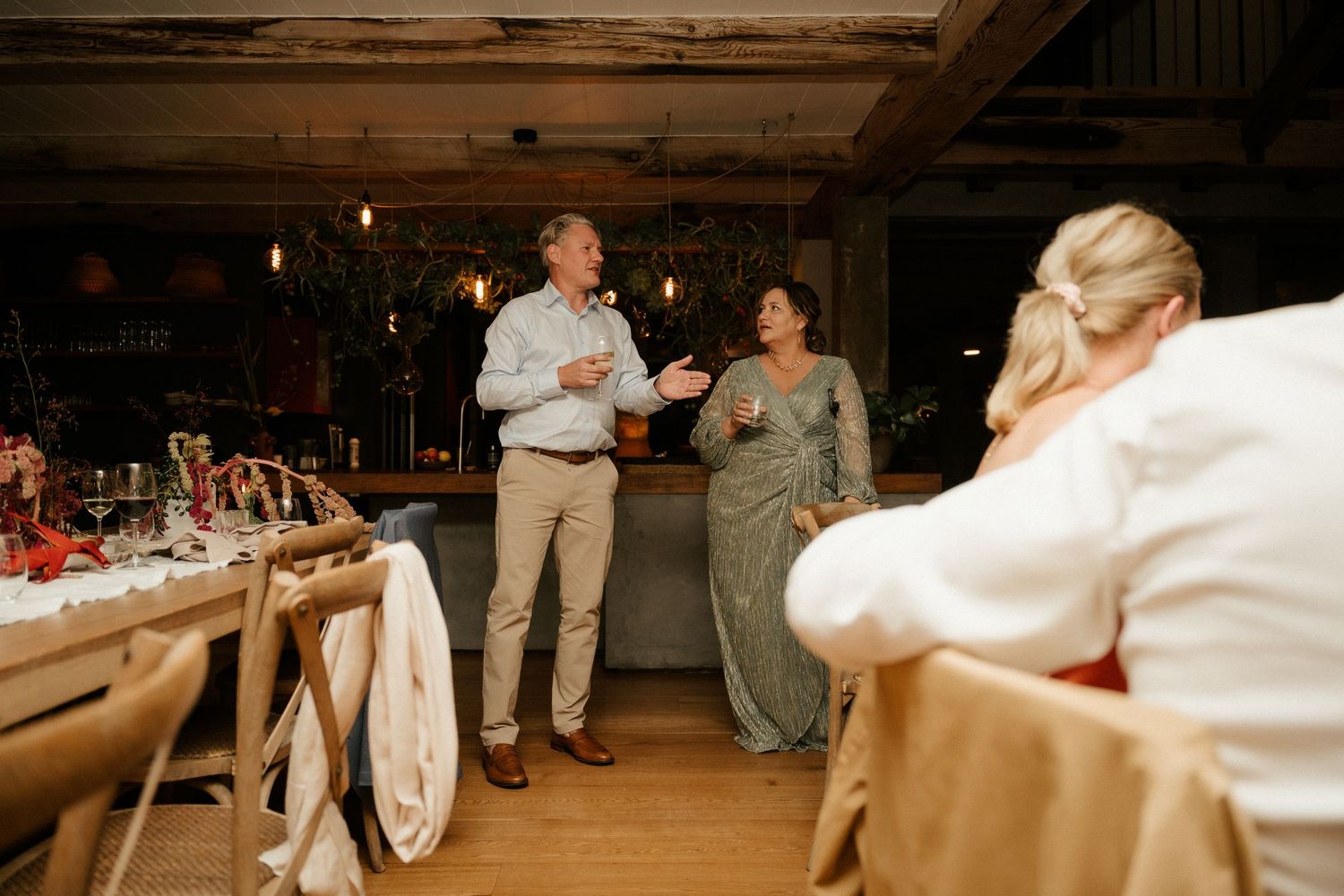 A warm and intimate moment captured during wedding reception speeches in a rustic venue.