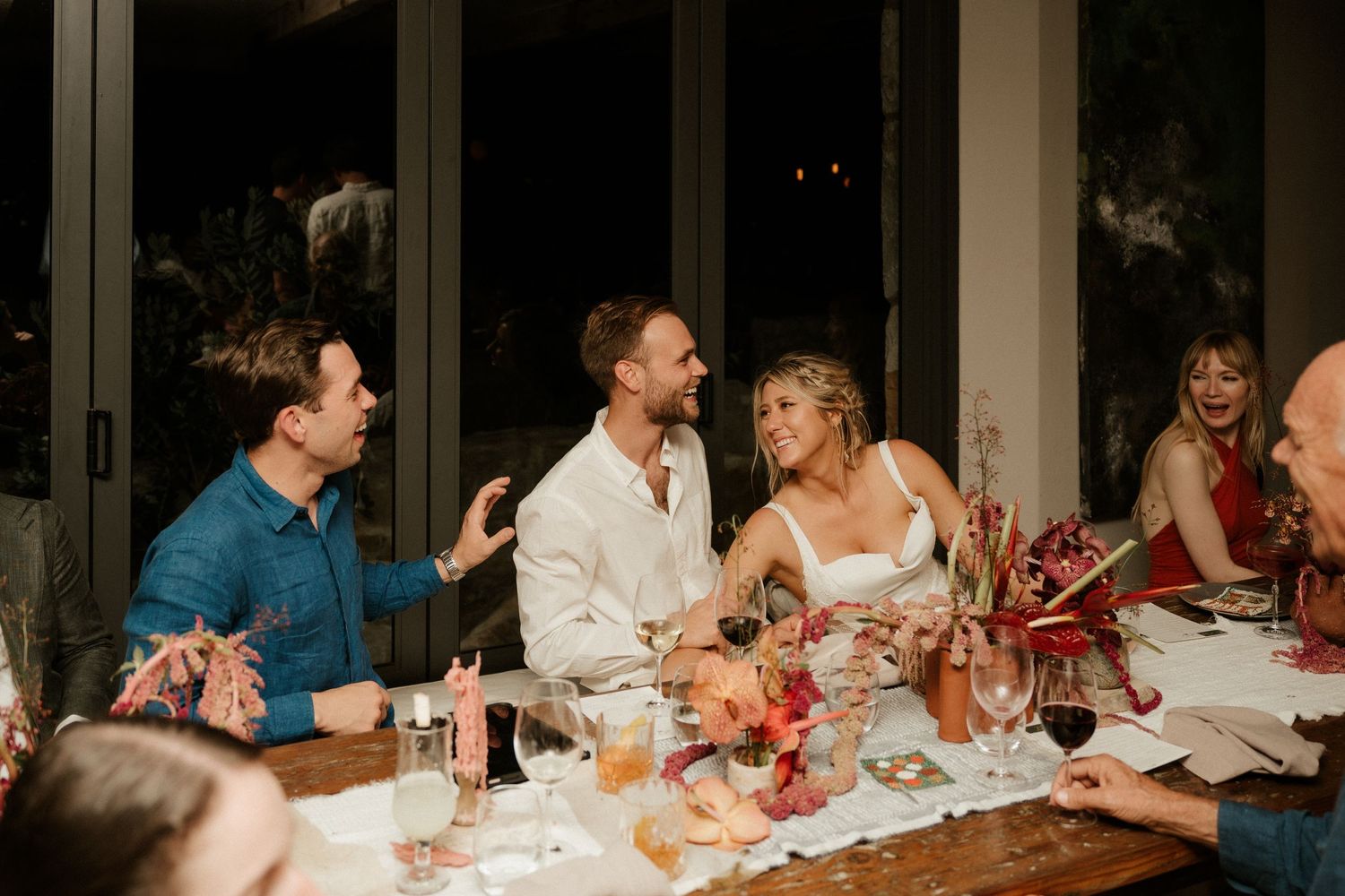 Guests enjoying lively conversation at decorated dinner table during evening celebration.
