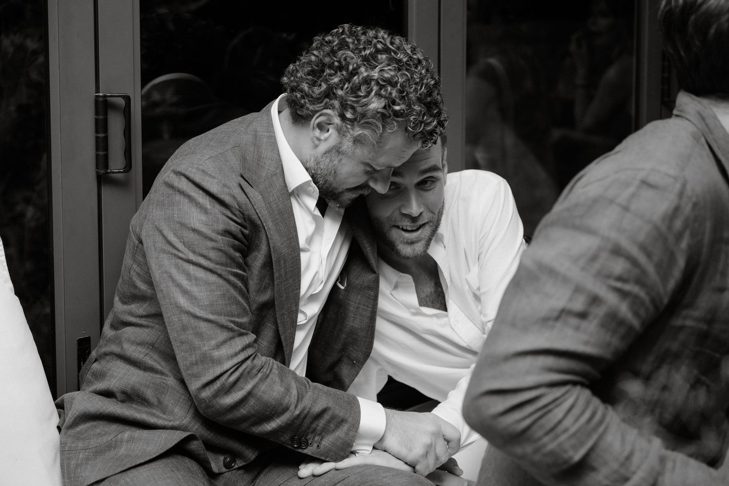Two guests share an intimate moment of laughter at a formal event.