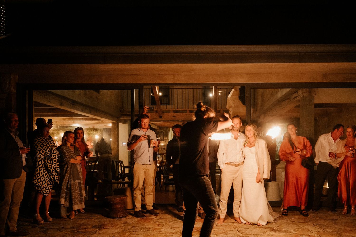 Wedding reception dance party in dimly lit rustic indoor venue with warm lighting.