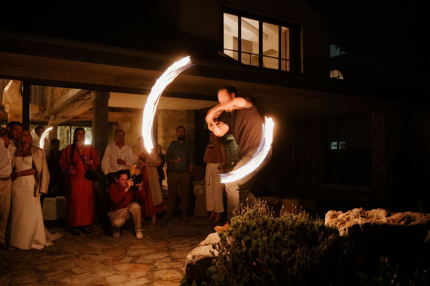 A fire performer creates circular light trails during a nighttime outdoor performance.