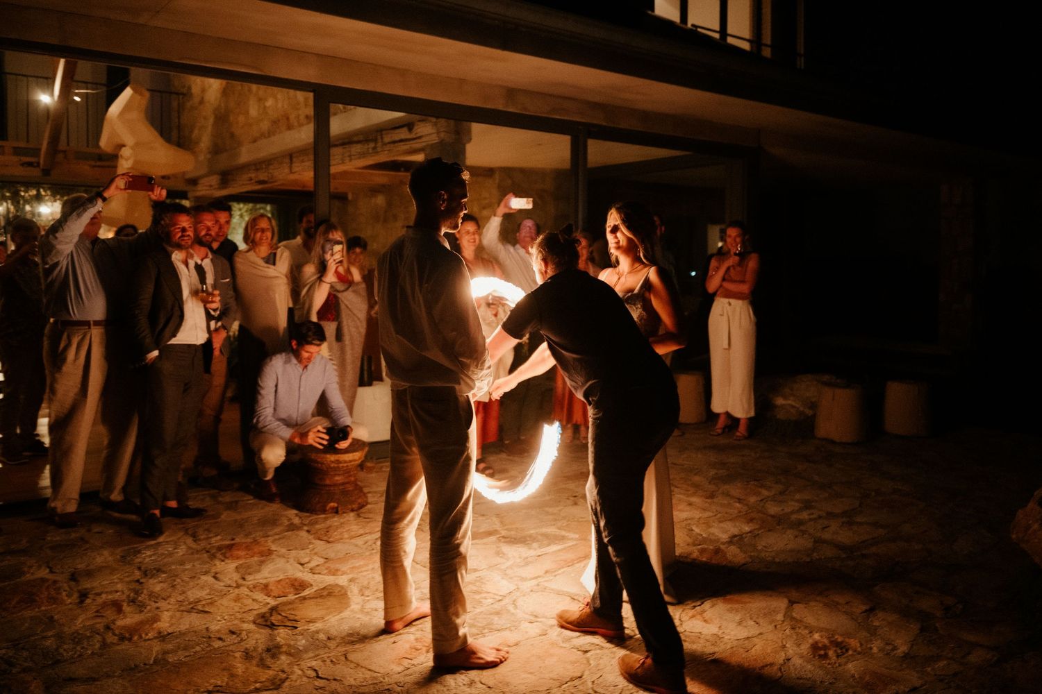 Nighttime party scene with guests gathered around sparklers creating a magical atmosphere outdoors.