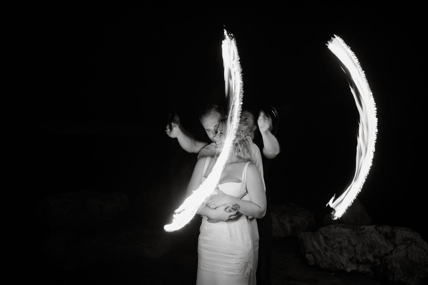 Person creating light trails with sparklers in the dark at nighttime celebration.
