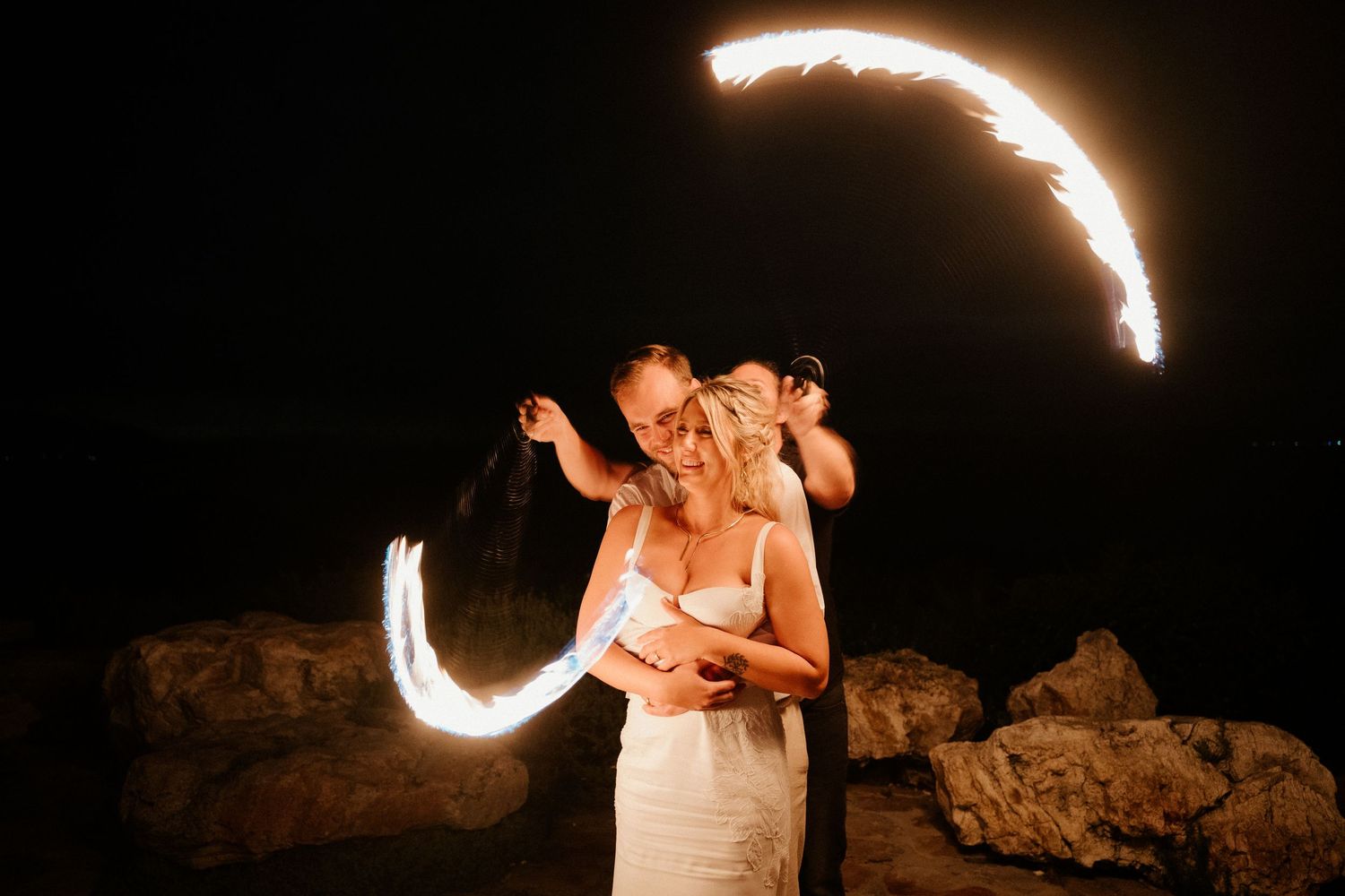 A romantic moment captured with swirling light trails against a dark rocky backdrop.