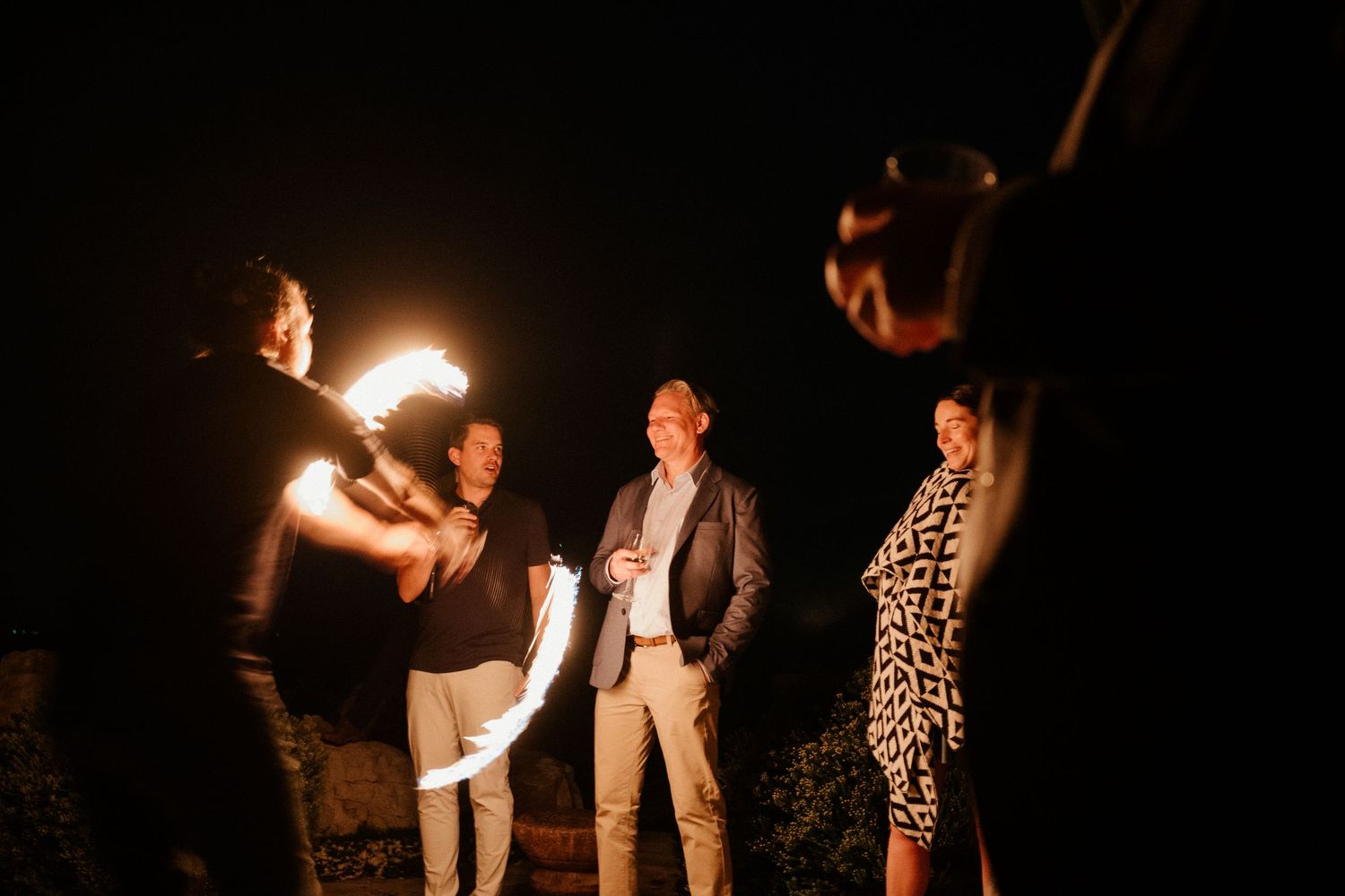 Group of people celebrating with sparklers in the dark outdoors creating a festive nighttime atmosphere.