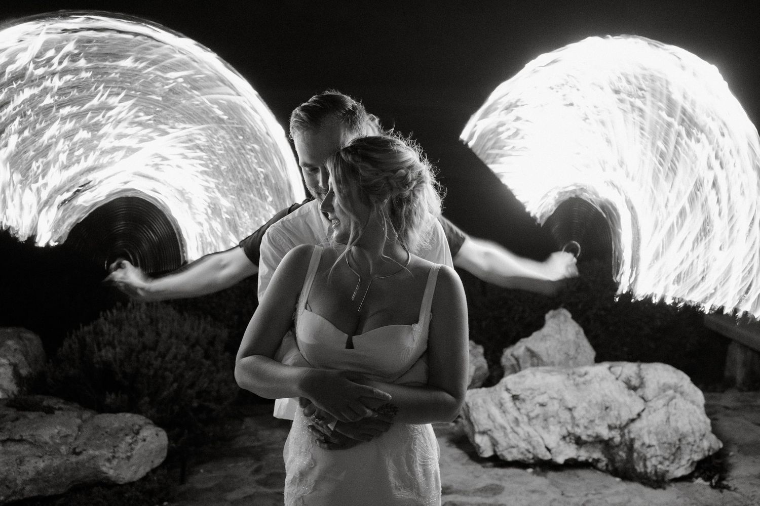 Couple embracing in front of dramatic circular light installations at night.